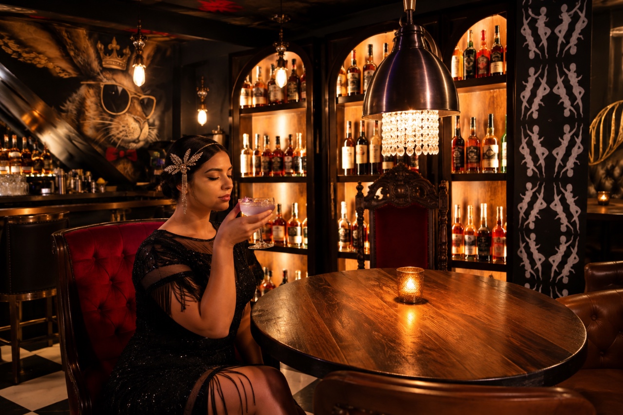 The bar at Bad Rabbit, lined with leather stools under crystal chandeliers, bottles stacked behind a gilded rabbit mural.